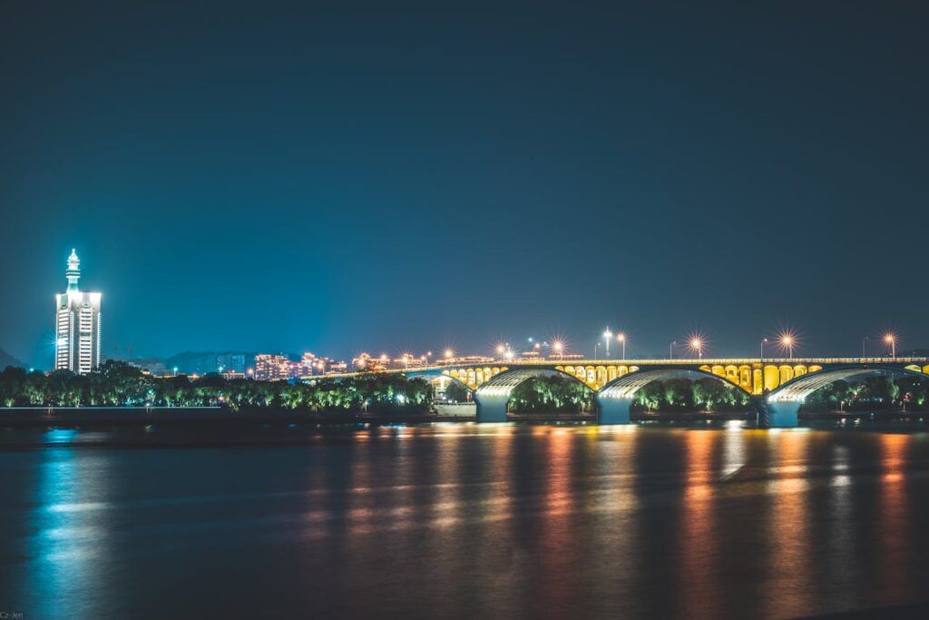 pexels photo 10047720 A stunning nighttime view of an illuminated bridge reflecting over a calm river.