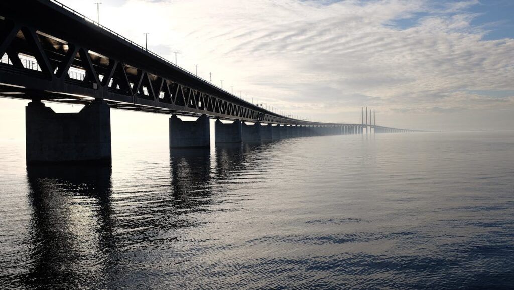 pexels photo 128362 A stunning view of a large steel bridge reflecting on the tranquil water under a cloudy sky.
