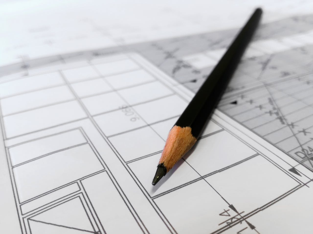services-03 Detailed image of a black pencil resting on architectural blueprints, ideal for design and planning themes.
