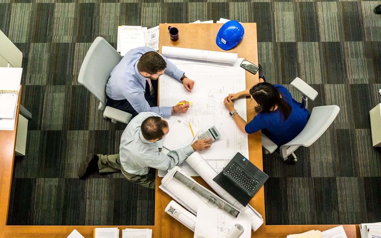 about-us Top view of a team working on construction plans in an office setting.